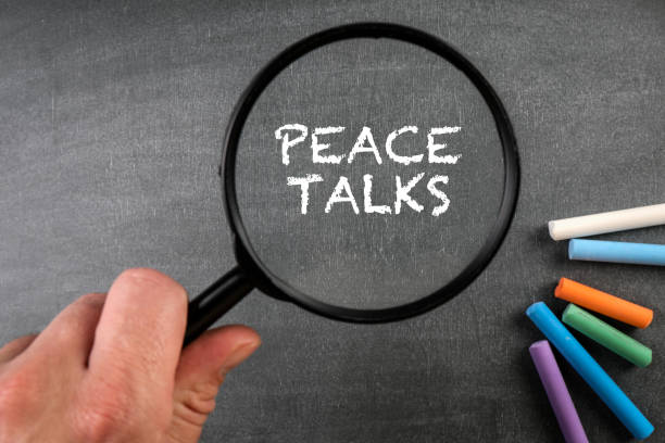 istock Peace Talks. Magnifying glass and colored pieces of chalk on a dark board 1383010820