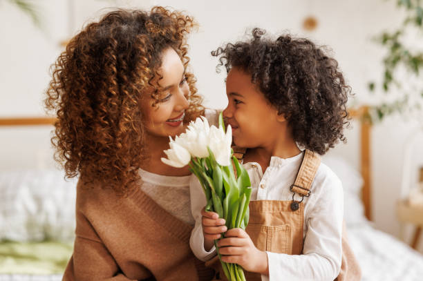 istock Grateful ethnic mother with bouquet hugging son 1383013886