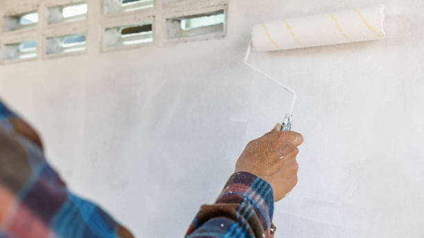 istock hand of a painter holding a plot to paint the white wall 1383015728