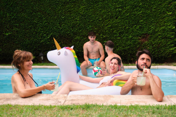 istock Group of people drinking lemonade and having fun in a swimming pool. 1383016927