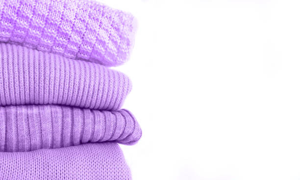 Stack of knitted warm purple sweaters isolated on white background