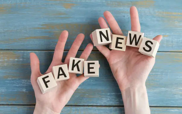 Photo of The word Fake News written with wooden scrabble blocks on hands