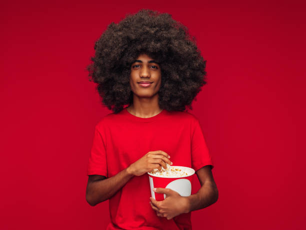 Beautiful afro men eating popcorn isolated red background