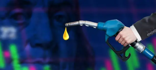 Oil dripping from a gasoline pump on financial data analysis graph showing market trends over American dollar