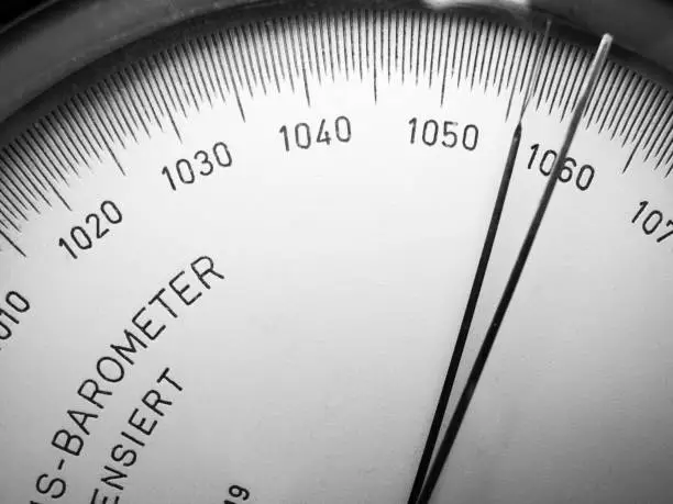 Close-up view of the scale with pointer of an analogue barometer monochrome.