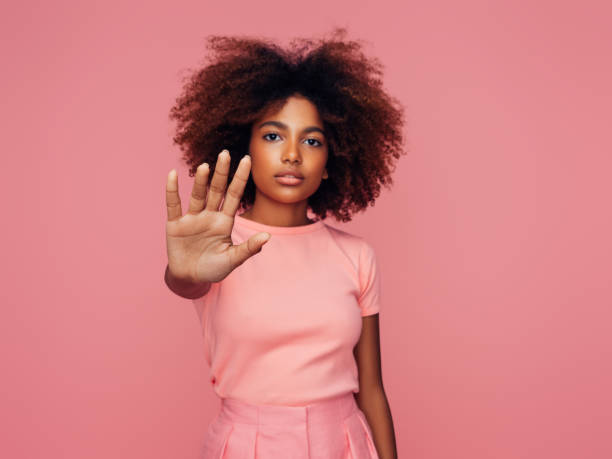 belle fille afro avec la coiffure bouclée affichant le signe d’arrêt - t shirt shirt pink blank photos et images de collection