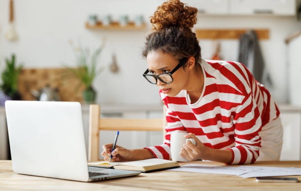 istock Focused african american female freelancer looking at laptop taking notes during remote team meeting 1383034723