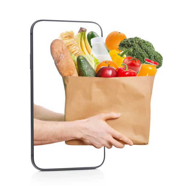 The concept of food and groceries delivery. Hands with a bag of food in a smartphone The concept of food and groceries delivery. Hands with a bag of food in a smartphone home delivery photos stock pictures, royalty-free photos & images
