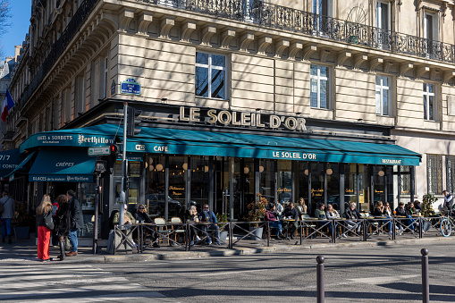 2022 Cafe terrace on the right bank of Paris, France. There are tourists and locals having a snack outside in the winter sunshine.