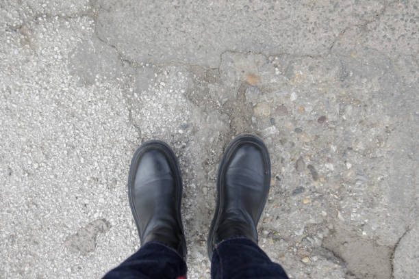 istock Person in chunky platform leather boots on asphalt, top view 1383037866