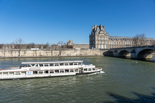 2022 River Seine cruiser in Paris, France. There are tourists and locals outside in the winter sunshine.