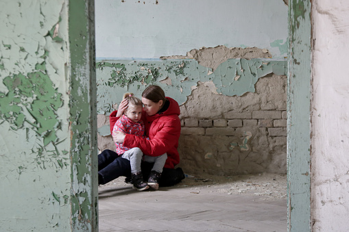 Madre y su hija en construcción destruida. Concepto de guerra, refugiados, crisis de guerra. photo