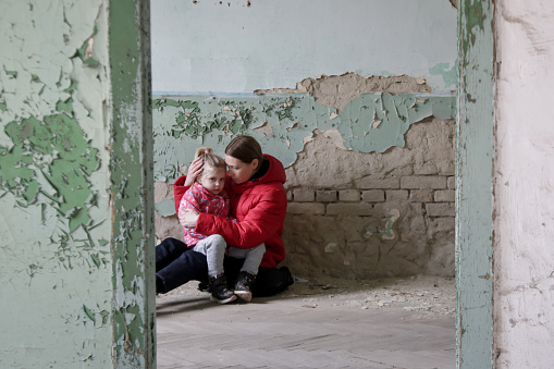 Mother and her daughter in destroyed buildng. War, refugees, war crisis concept.