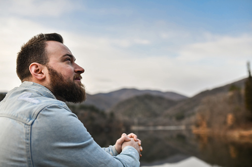 Bearded Male Clasping Hands And Looking Hopefully Towards Sky While Feeling Motivated For Future