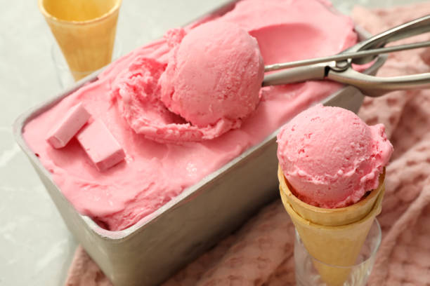 istock Delicious ice cream in container and wafer cones on table, closeup 1383046046