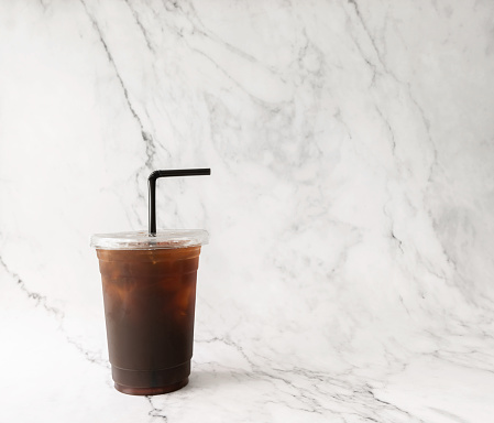 Asian black Iced coffee on the plastic cup on white marble background. copy space for tour text