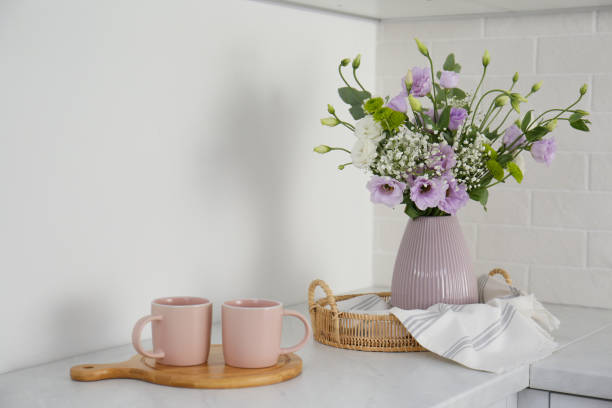 istock Beautiful bouquet with Eustoma flowers and cups on table indoors 1383051168