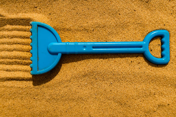 children's plastic rake lying on the yellow sand