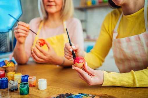 Mother and daughter painting Easter eggs at home