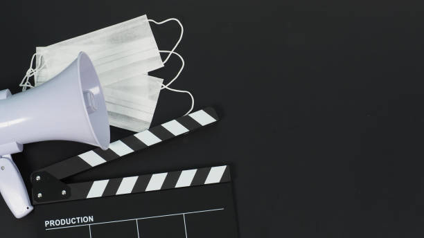 istock Black clapperboard with face mask and megaphone on black background. 1383074549