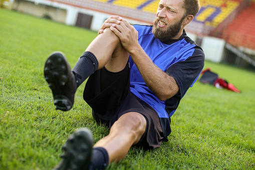 Soccer player injured during a training on a field. About 30 years old, Caucasian male.