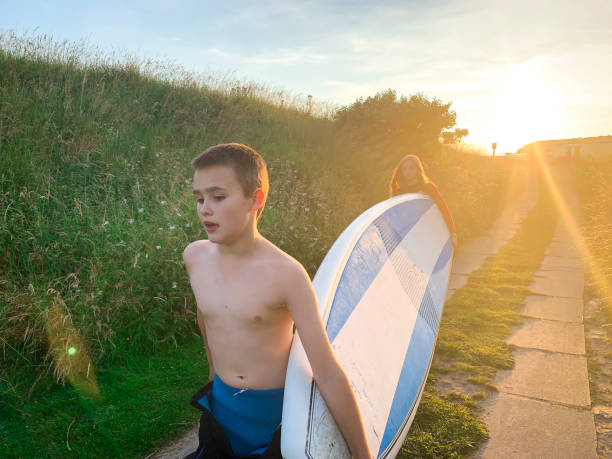 Cute little blond boy stand on the surfboard learning balance practicing surfing before going to the sea
