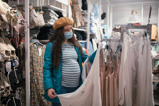 donna incinta che acquista abbigliamento in una boutique. - human pregnancy clothing shopping retail foto e immagini stock