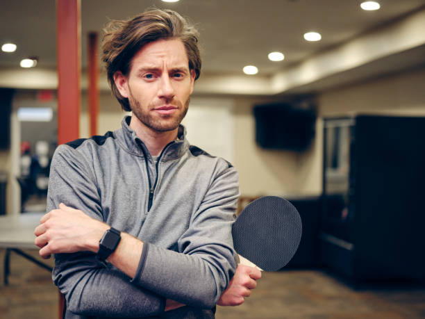 A portrait of a male ping pong player in an office.