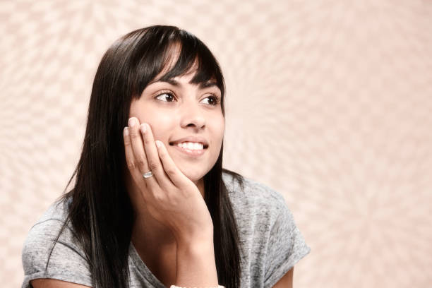 istock Beautiful young dark-haired woman sits serenely, lost in thought, against patterned checked background 1383095475