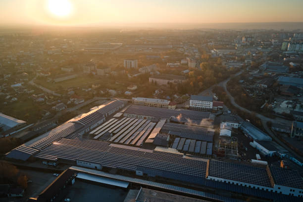 青い太陽光発電パネルの空中写真は、緑の生態学的電気を生産するための工業用建物の屋根に取り付けられています。持続可能なエネルギー概念の作成 - land development aerial view planning ストックフォトと画像