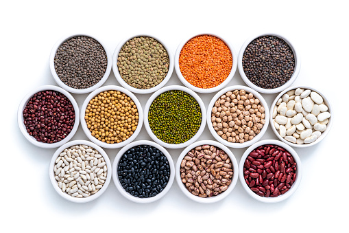 Dried legumes assorted in many bowls isolated on white background including lentils, chickpeas, soybeans and beans