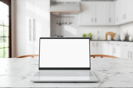 Laptop With Blank Screen On Empty Marble Dining Table With Wooden Chairs And Defocused Kitchen Background