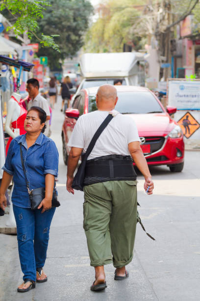 completely bald thai adult man is walking in street of bangkok - completely bald fotos imagens e fotografias de stock