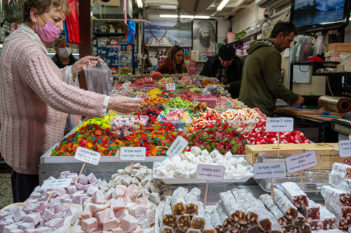 TEL AVIV, ISRAIL - January 25, 2022: Israelis shop at the Carmel Shuk HaCarmel Market in Tel Aviv, Israel. This is a very popular market in Tel Aviv where they sell confectionery as well as fruits and.