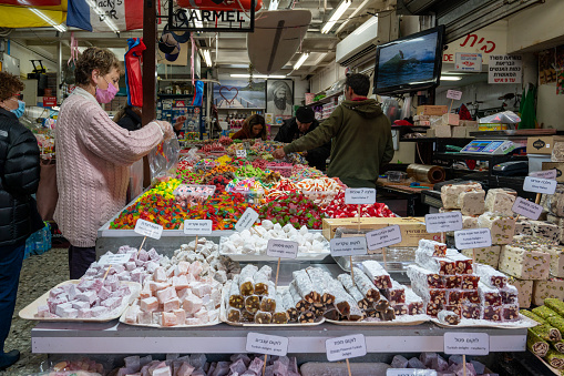 TEL AVIV, ISRAIL - January 25, 2022: Israelis shop at the Carmel Shuk HaCarmel Market in Tel Aviv, Israel. This is a very popular market in Tel Aviv where they sell confectionery as well as fruits and.