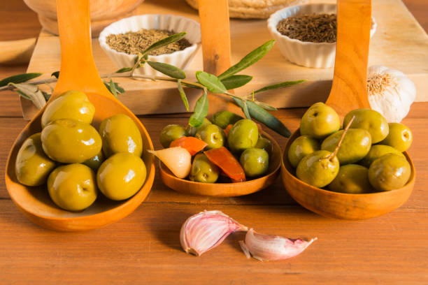 Fresh mixed olives on display at deli counter in a busy rotisserie shop for takeaway.