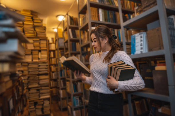 istock gorgeous beauty sitting in the library serious and reading a super book. 1383107203