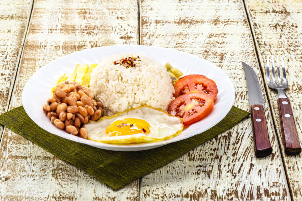 istock rice dish with Brazilian beans, served with salad, fried egg and farofa. Served on a rustic table 1383109377