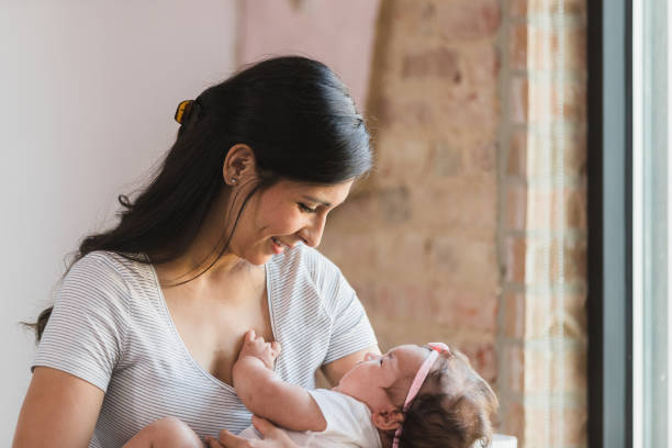 istock Smiling mom looks down at baby in her arms 1383109933