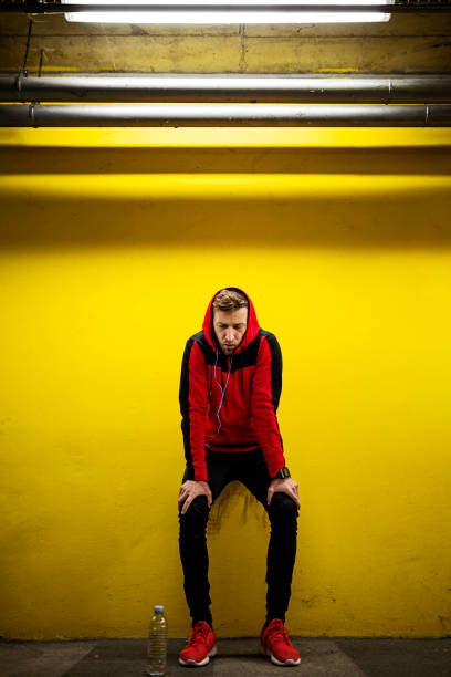 istock Young runner take a break after training leaning on a yellow wall 1383110477