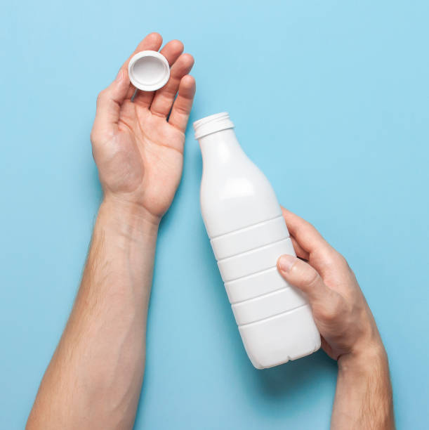 istock White plastic bottle containers for dairy products in male hands on blue background top view flat lay. Plastic Kefir Yogurt Milk Bottle. Packaging template mockup. Layout for your design 1383113667