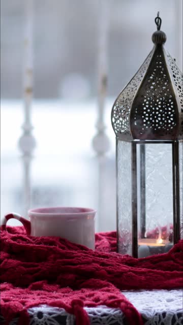 Ramadan lantern with candle inside and hot tea into mug with steam rising