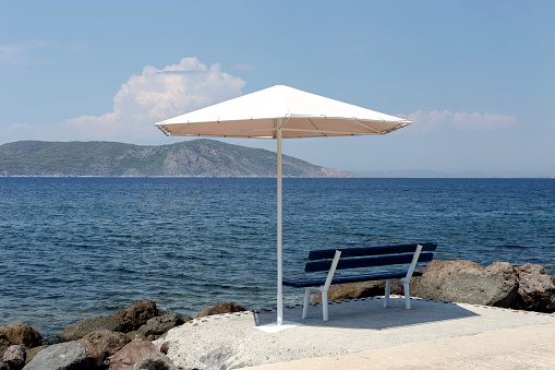 Seascape. The benches and sun umbrellas on the beach on the background of the sea and mountains