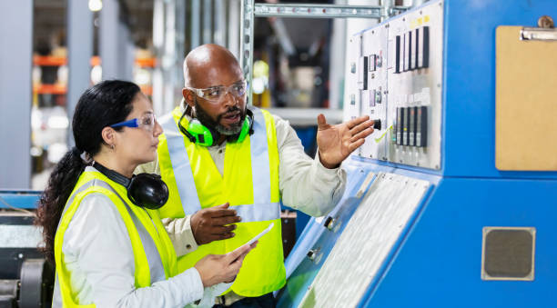 Multiracial workers in factory at machine control panel stock photo