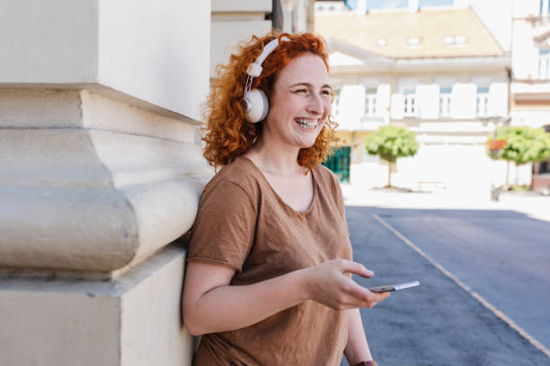 istock Redhead woman using mobile phone outdoors and listening to online content 1383126485