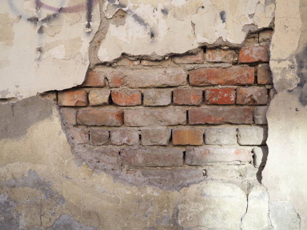 istock the bricks are visible from under the plaster. Part of the cement coating has fallen off the old brick wall. Building renovation. Builders' mistakes. Temporary and weather influence 1383127948