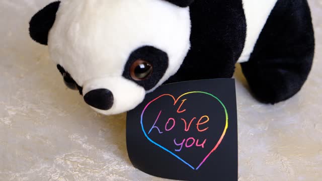 Note I love you for Valentines Day with cute panda toy. Art scratch paper for message