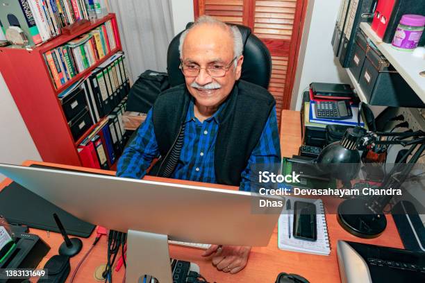 Bogotá Colombia A Grayhaired 74 Year Old Asian Indian Man Working From His Home Office On His Desktop Computer Appears Amused By Something On His Screen Stock Photo - Download Image Now