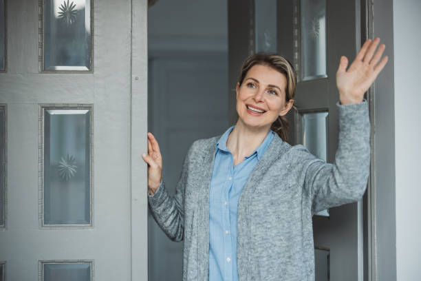 istock Woman standing at hose front door 1383133161