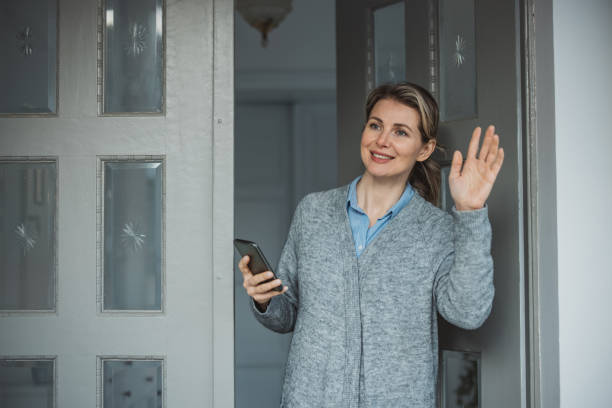 istock Woman standing at hose front door 1383133177